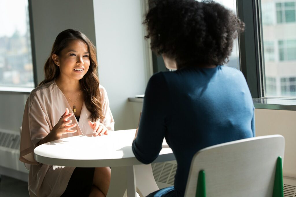 two women sitting on chair discussing CRM Consultant vs. CRM Software